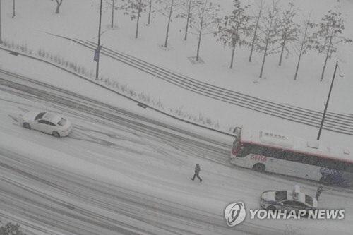경기북부 일대에 대설주의보가 내린 28일 오전 경기도 의정부시 경기도청북부청사 앞에서 차량이 오르막길에 멈춰서자 경찰이 도로를 통제하고 있다. /연합뉴스